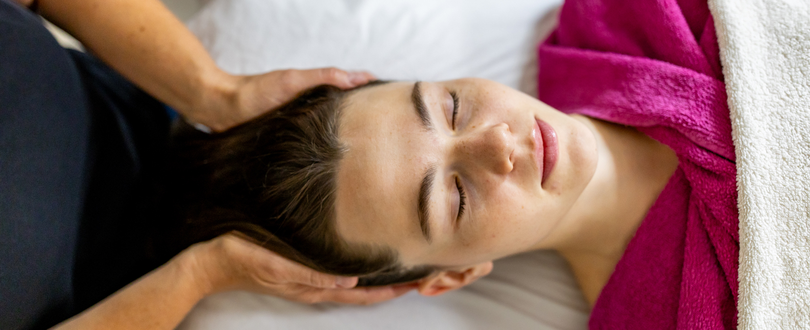 Entspannt liegende Frau bekommt Gesichtsbehandlung