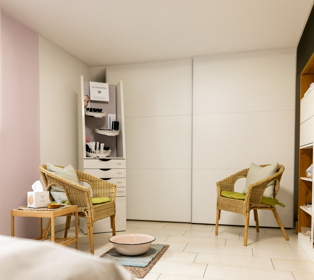 Wartezimmer mit bequemen Korbstühlen, Taschentücher auf dem Tisch daneben, bereitgestellter Wasserschale auf dem Boden und Regalen