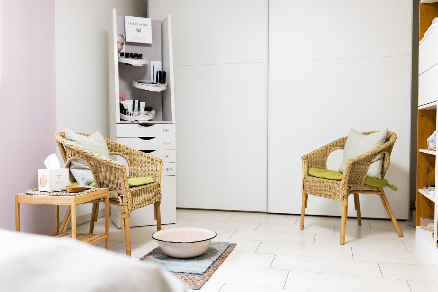 Wartezimmer mit bequemen Korbstühlen, Taschentücher auf dem Tisch daneben, bereitgestellter Wasserschale auf dem Boden und Regalen